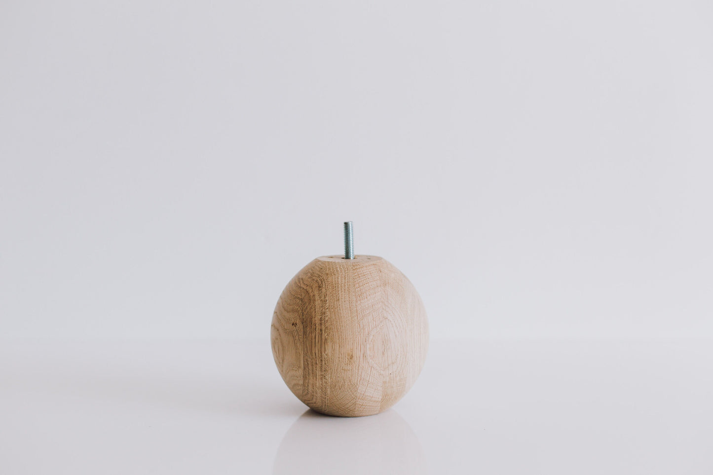 A single round turned wooden leg with a sphere shape on top, displayed against a white background.