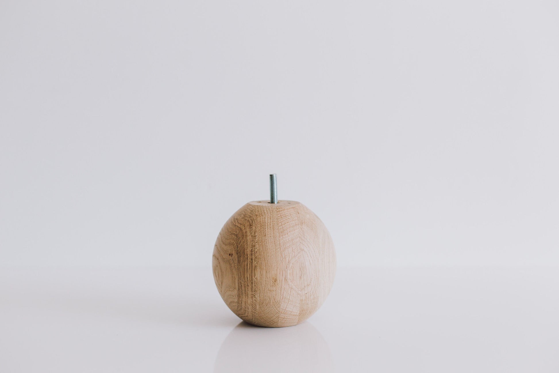 A single round turned wooden leg with a sphere shape on top, displayed against a white background.