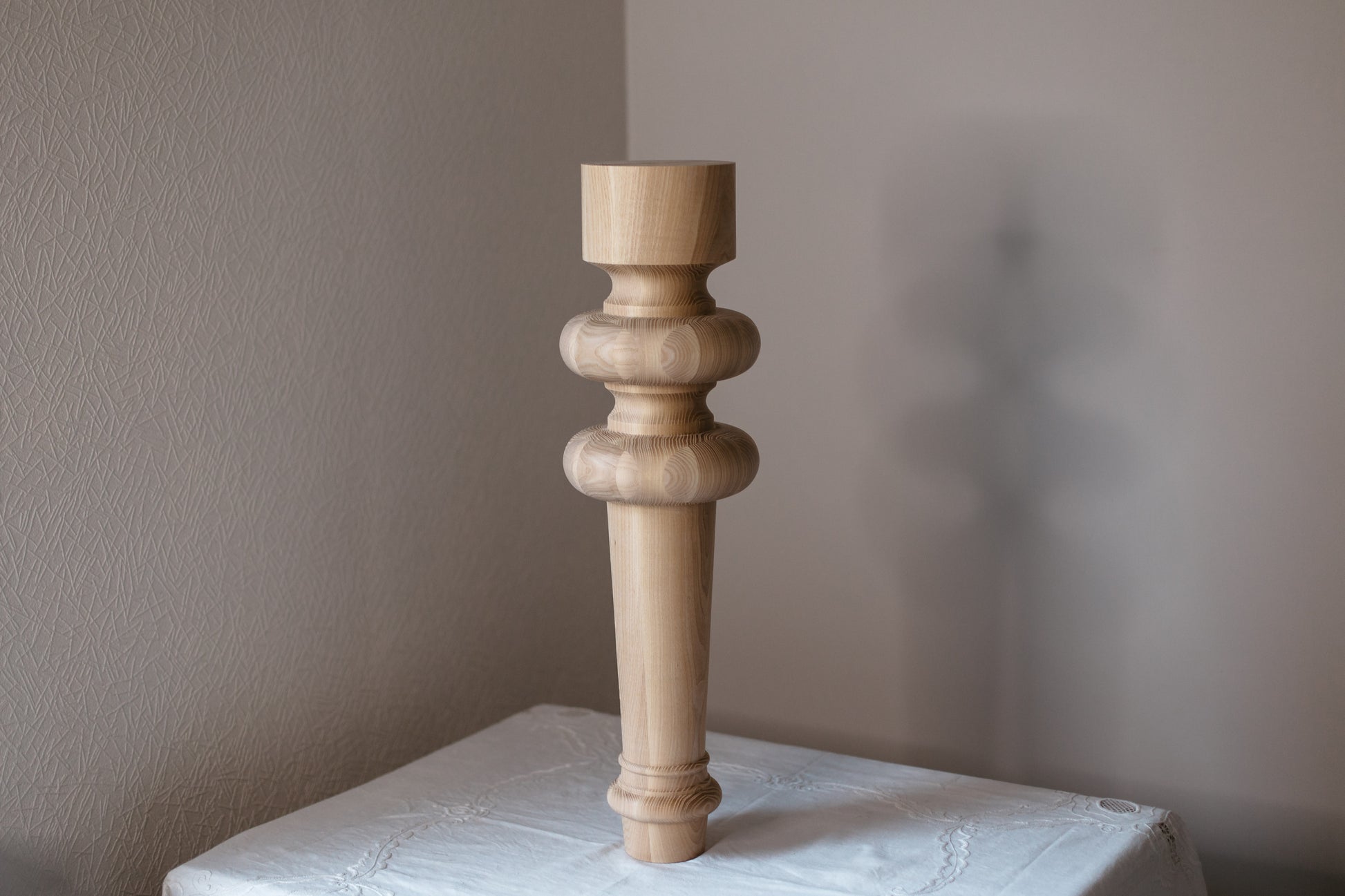 Wooden candlestick on a textured surface with a neutral background