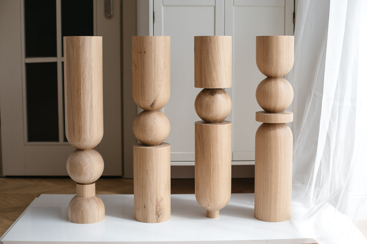 Set of four wooden candle holders on a white surface with a neutral background