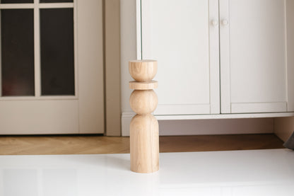 Wooden leg of a piece of furniture on a white floor with cabinets in the background