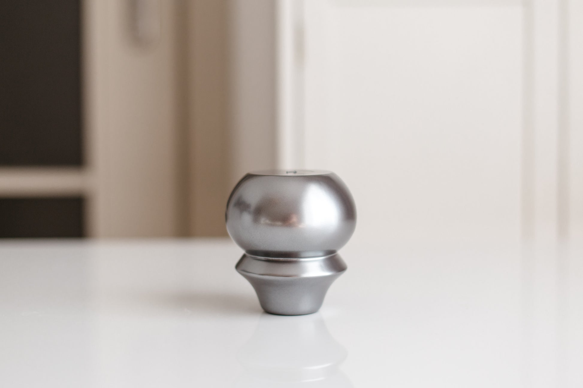 Metallic knob on a white surface with a blurred background
