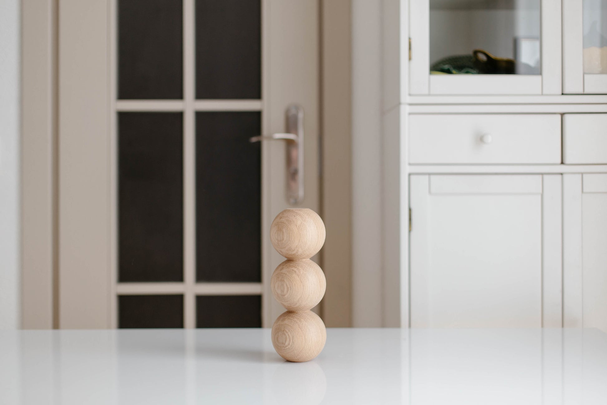Stack of wooden spheres on a white surface with a blurred background