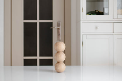 Stack of wooden spheres on a white surface with a blurred background