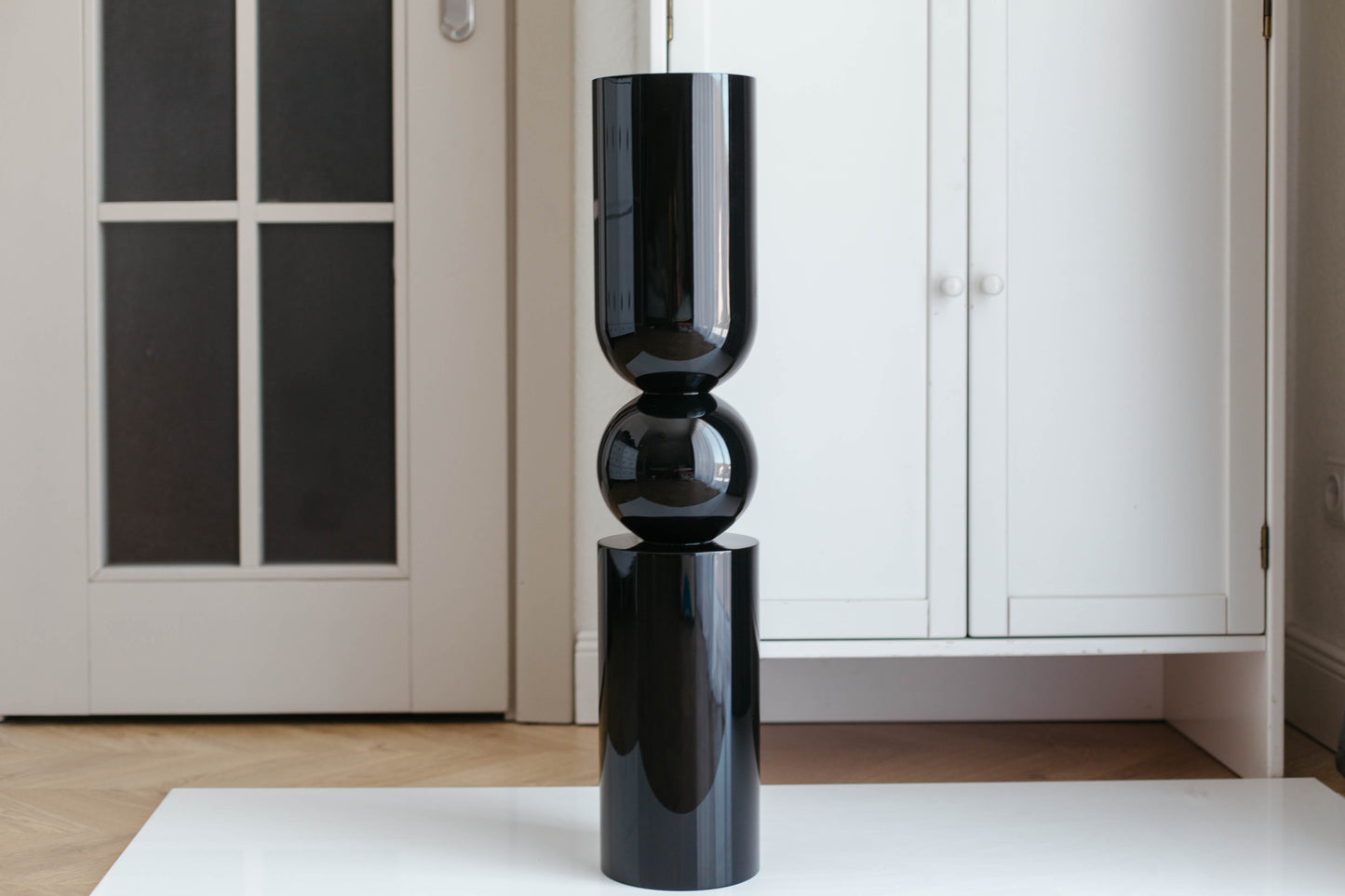 Black cylindrical vase on a white surface with a neutral background